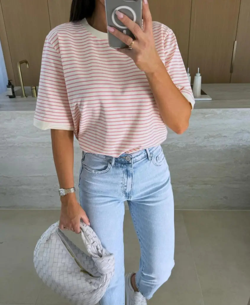 light blue woven handbag with a structured rounded shape and textured surface paired with a striped short sleeve t shirt casual summer top