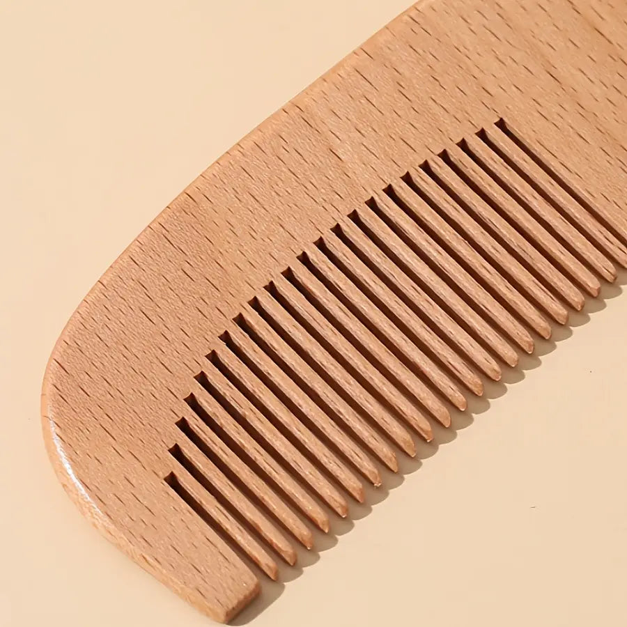 A smooth light brown wooden comb with evenly spaced teeth and a curved handle from the baby wooden grooming set and healthcare kit.