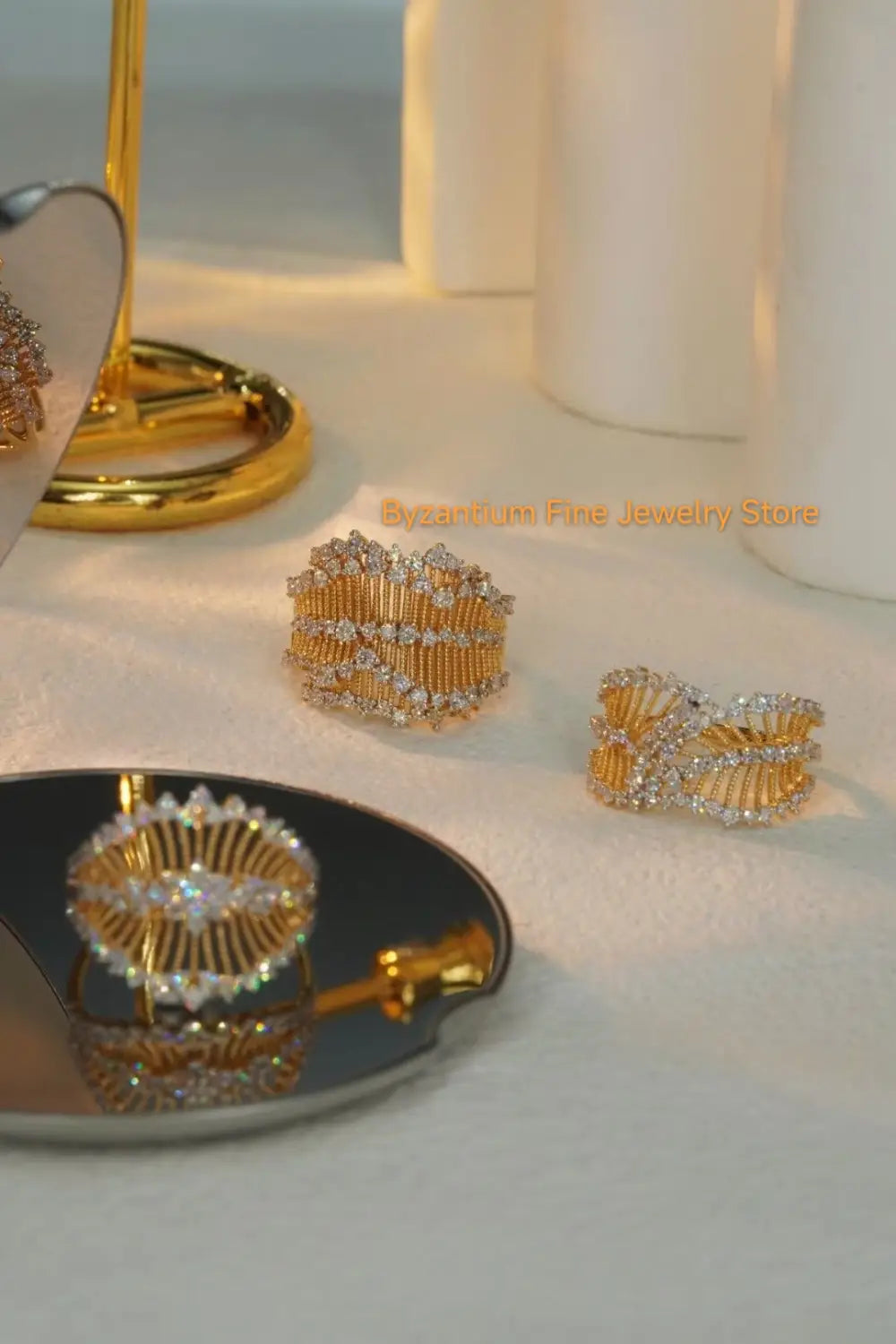 Goldfarbene, aufwendig gestaltete Ringe, besetzt mit funkelnden klaren Steinen, kombiniert mit Ohrringen mit silbernen Tropfenquasten in Gold-Vermeil-Material.