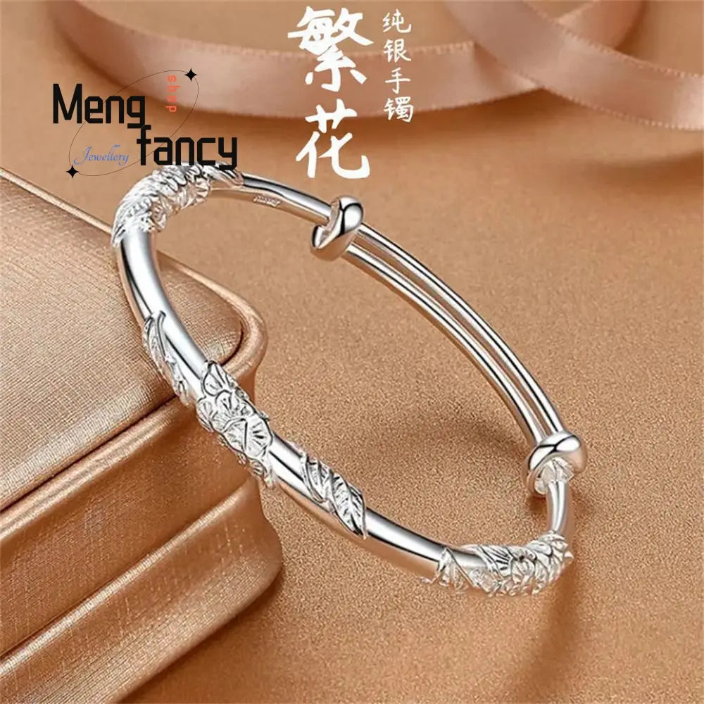 a delicate silver sliding bangle bracelet featuring intricate floral and leaf engravings with a classic adjustable clasp design, complemented by a natural jade raw stone centerpiece.