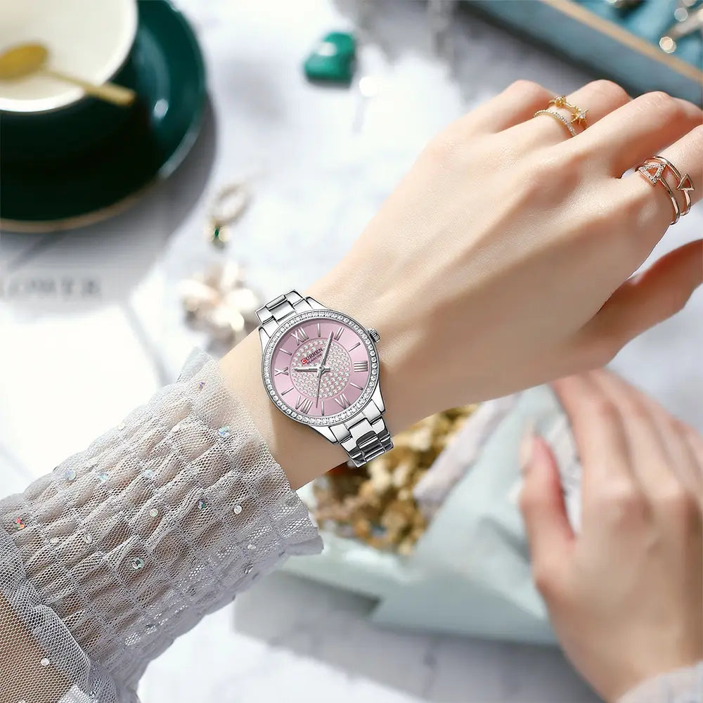 Silver-toned Curren women stainless steel crystal quartz watch with a pink dial featuring sparkling crystals roman numerals and a sleek stainless steel bracelet