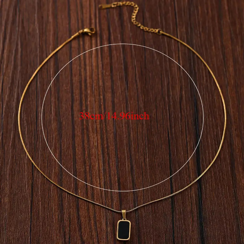 Collier médaillon rectangle en or pour femmes, avec une chaîne ton or et un pendentif rectangulaire en émail noir élégant.