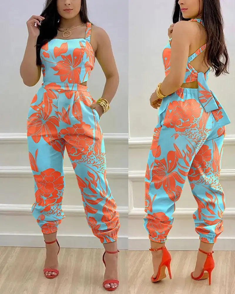 A vibrant turquoise and coral floral print women summer printed cutout jumpsuit featuring a halter neckline side cutouts and cuffed hems.