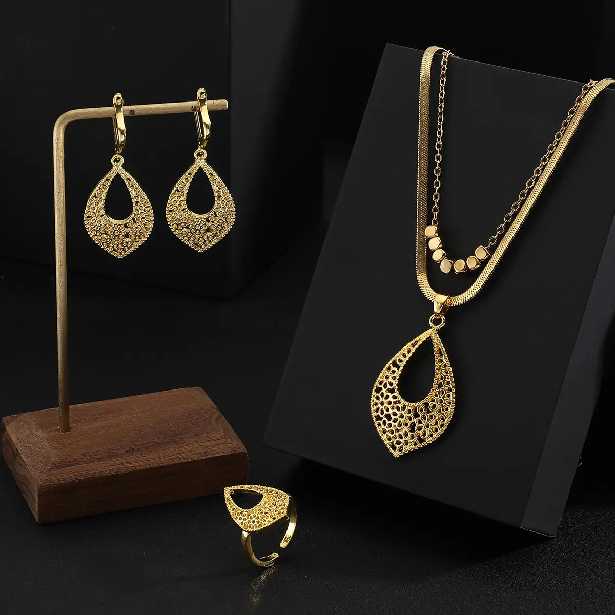 Juego de joyería de acero inoxidable color dorado para mujeres, con un collar con dije de lágrima calado intrincado en color dorado, aretes y anillo a juego.