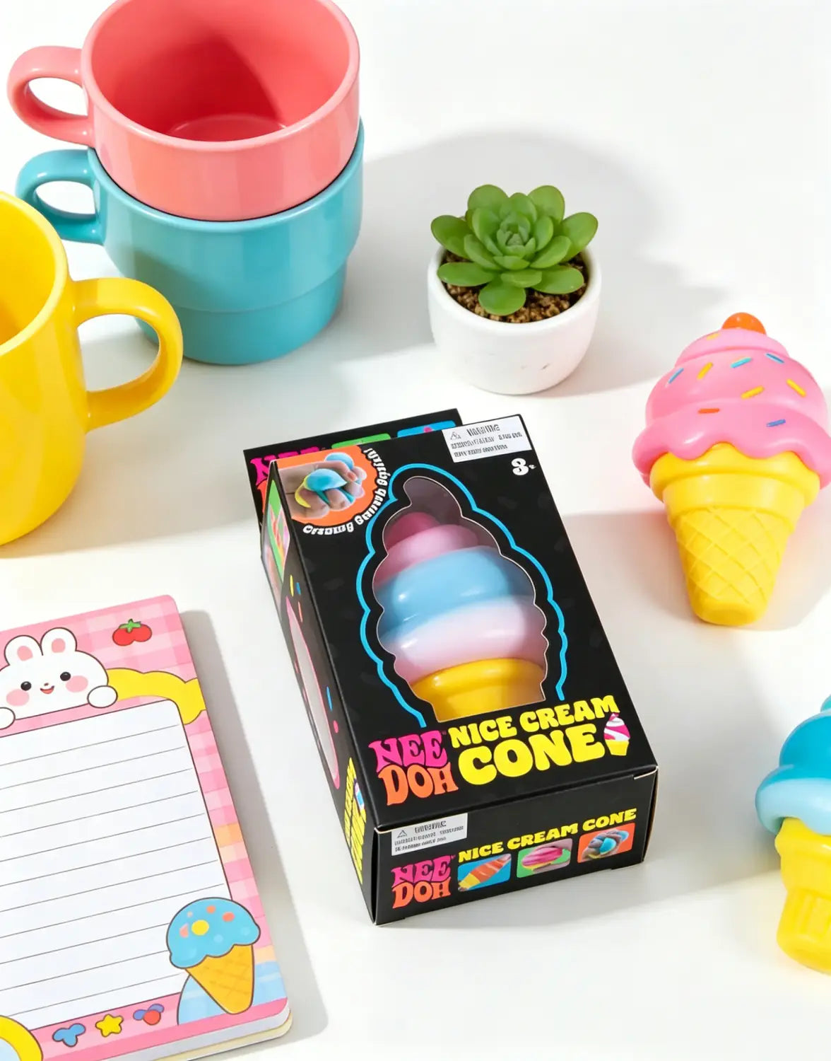 Ein farbenfrohes Eistüten-Eiscreme-Kegel-Nee-Doh-Spielzeug, geformt wie ein geschichteter Eistüten-Eiscreme-Kegel in pink, blau und gelb mit Streuseln, von vorne gezeigt.