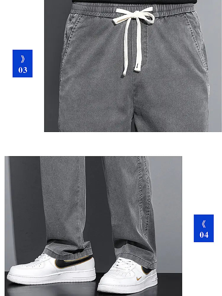 Men’s lyocell casual loose straight grey denim joggers with white drawstring waistband and rolled cuffs paired with white sneakers.