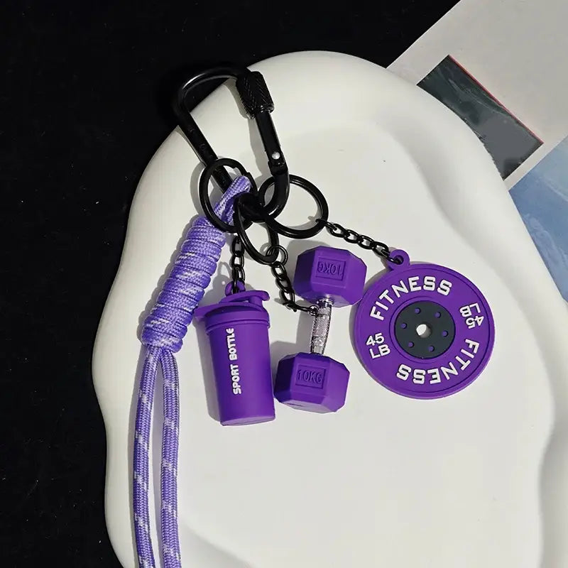 Porte-clés de musculation violet comprenant des breloques de bouteille shaker, d’haltère et de disque de poids, conçu comme accessoire de cadeau pour les amateurs de fitness.