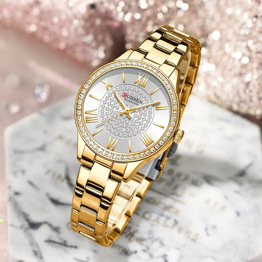 Curren women stainless steel crystal quartz watch featuring a gold-tone stainless steel bracelet, diamond-encrusted bezel, and roman numeral markers on a silver dial.