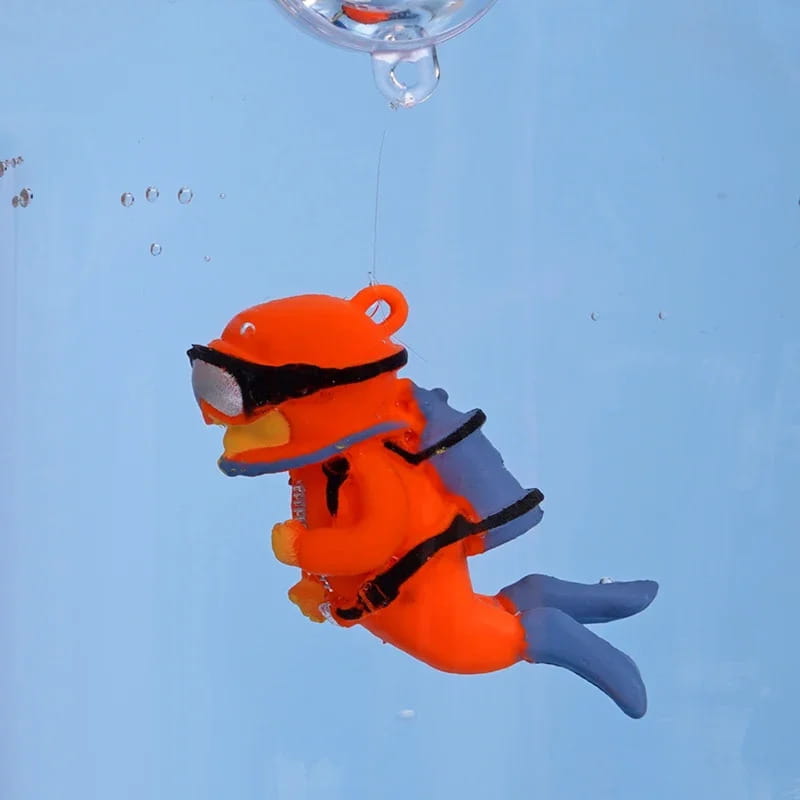 Orange plastic scuba diver toy with black goggles and blue fins designed as popular aquarium decoration for fish tank landscape decor and aquatic pet ornament accessory.
