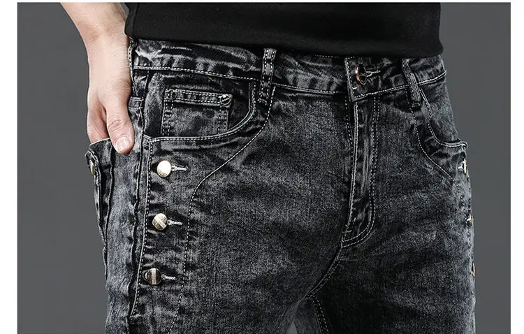 Jeans slim en denim extensible vintage pour hommes, lavage gris, avec tissu foncé délavé, usé et délavé, ainsi que des boutons à tonalité argentée sur les poches latérales.
