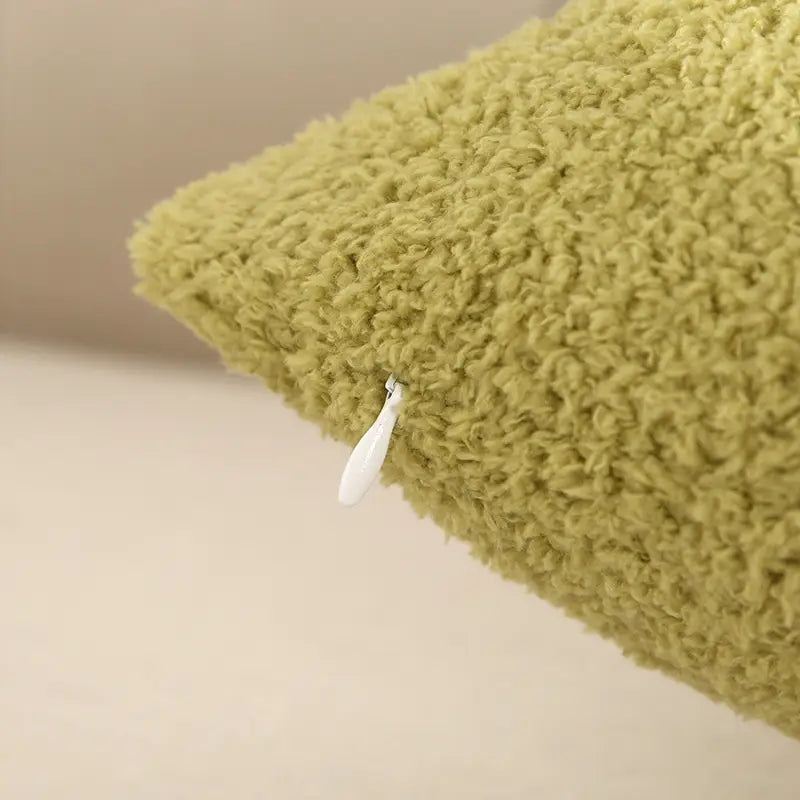 eine weiche olivgrüne 60x60-cm-Kissenhülle aus reinfarbigem Teddy-Veloursstoff mit einer plüschig strukturierten Oberfläche und einem weißen Reißverschluss-Zugstück