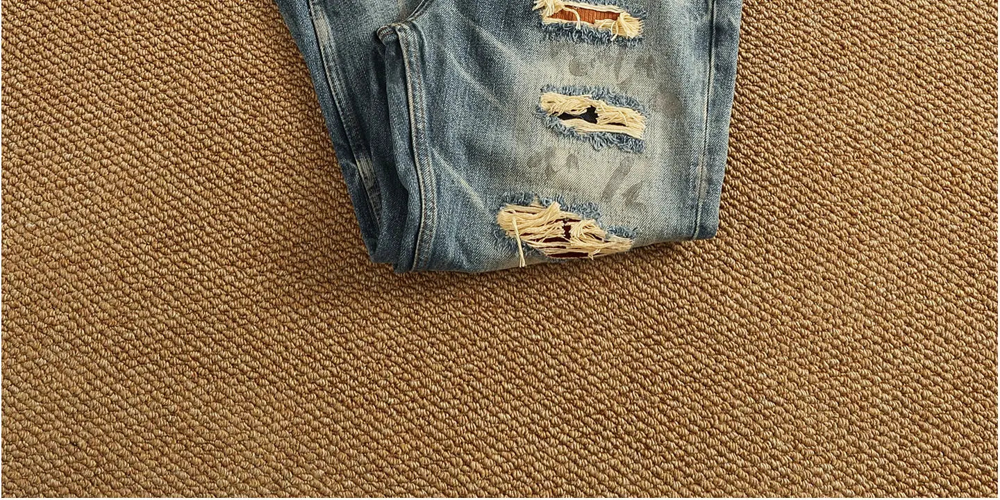 distressed patchwork denim jeans men featuring distressed blue denim with frayed ripped details along the thigh