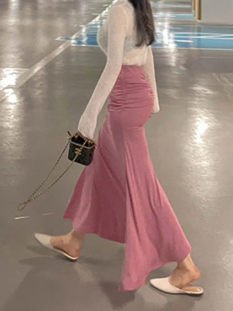 Ein zarter rosafarbener Meerjungfrauen-Midirock mit geraffter, hoher Taille, fließendem Stoff und einer figurbetonten Bundlösung.
