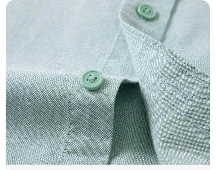 Camisa Oxford de algodón color azul claro, corte slim fit, para hombre, con textura sutil y botones verde menta a juego.