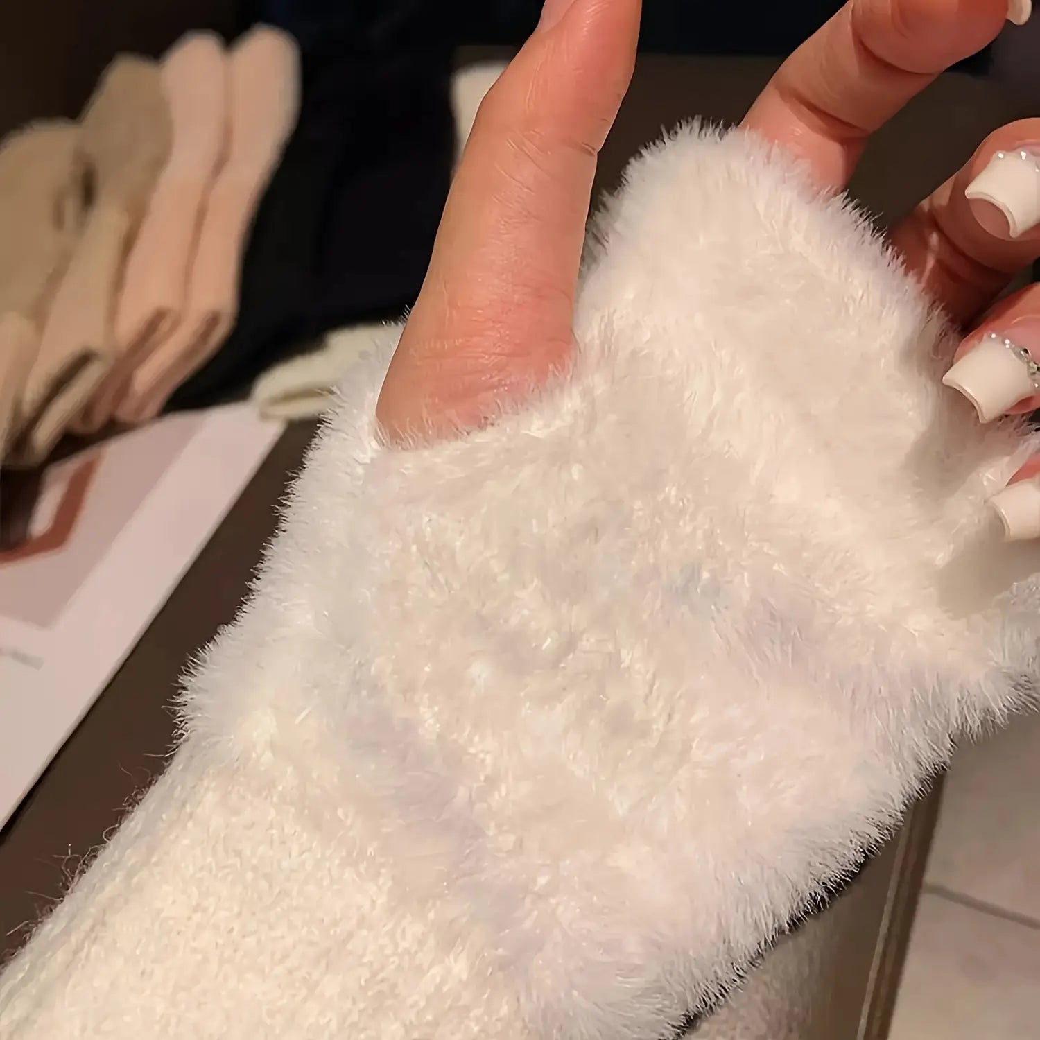 gants d’hiver sans doigts blancs et duveteux pour femmes, avec une texture pelucheuse douce, présentés du côté arrière