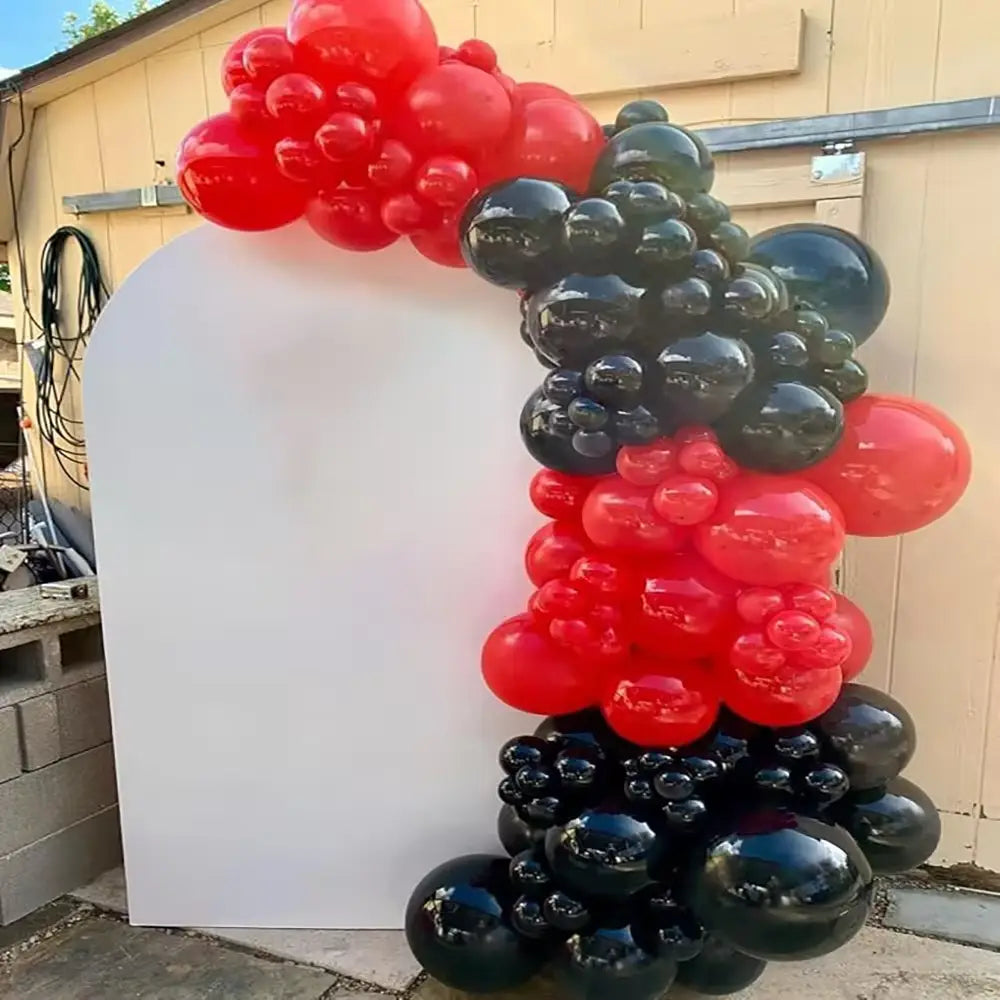 Ein lebendiger roter und schwarzer Ballonbogen mit glänzend aufgeblasenen Sphären, in einem kaskadenartigen Muster für die Partydekoration angeordnet.