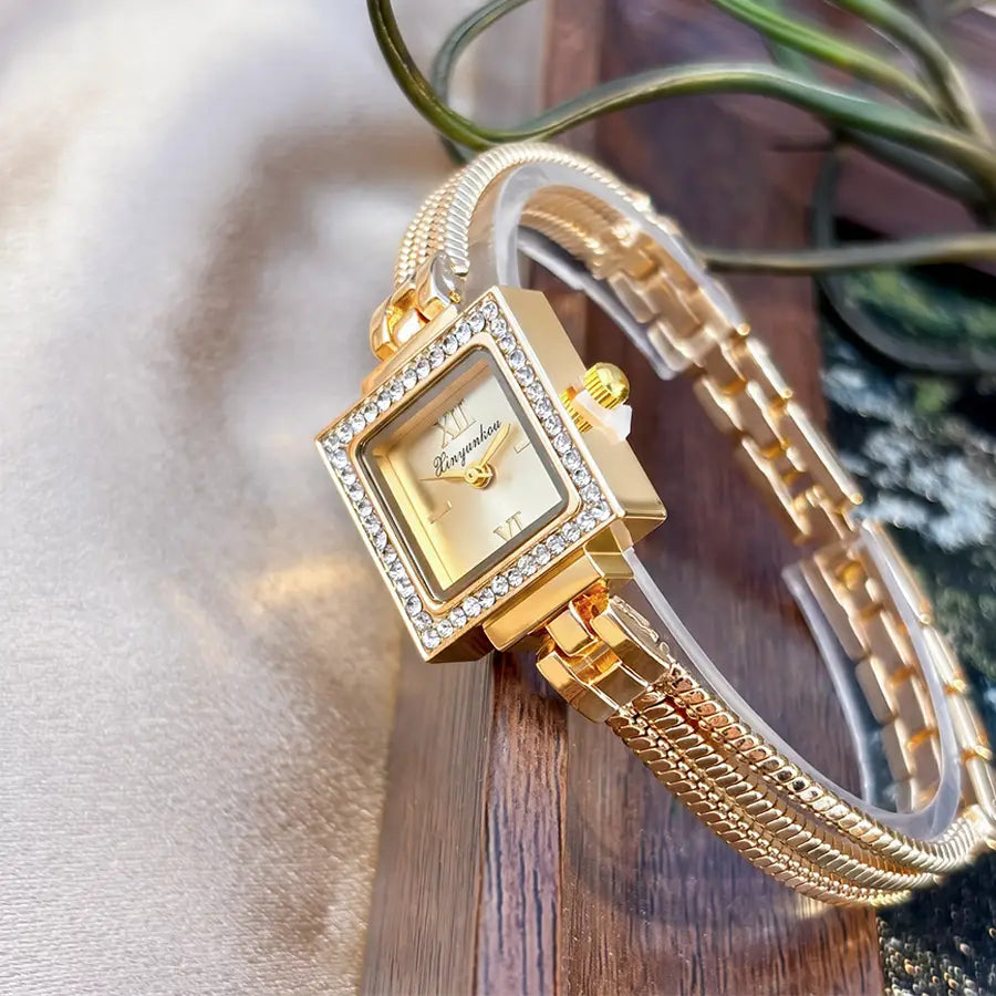 Gold-toned square watch with a diamond-studded bezel, roman numeral markers, and an elegant braided metal bracelet, designed as a vintage fringe strap.