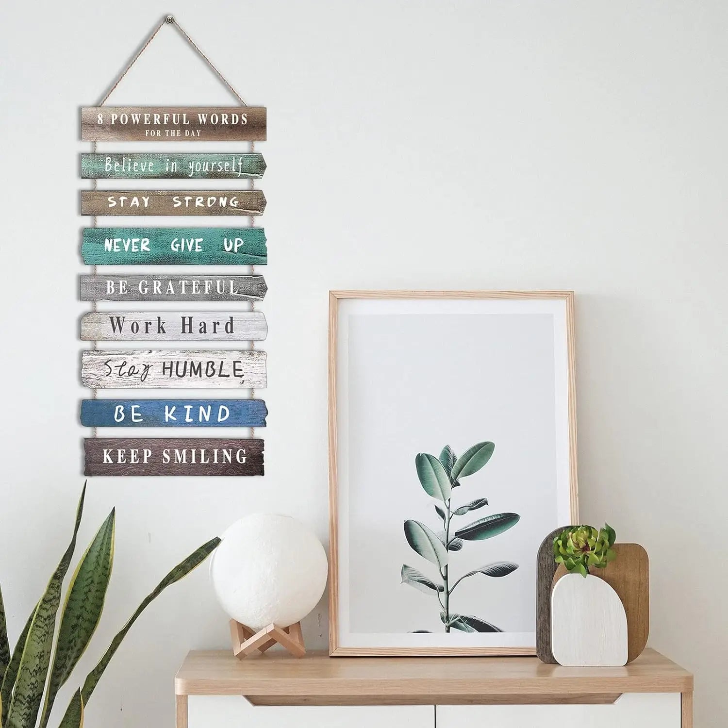 A rustic wooden wall art featuring eight horizontal planks painted in various shades of blue and brown with motivational phrases like believe in yourself and keep smiling.