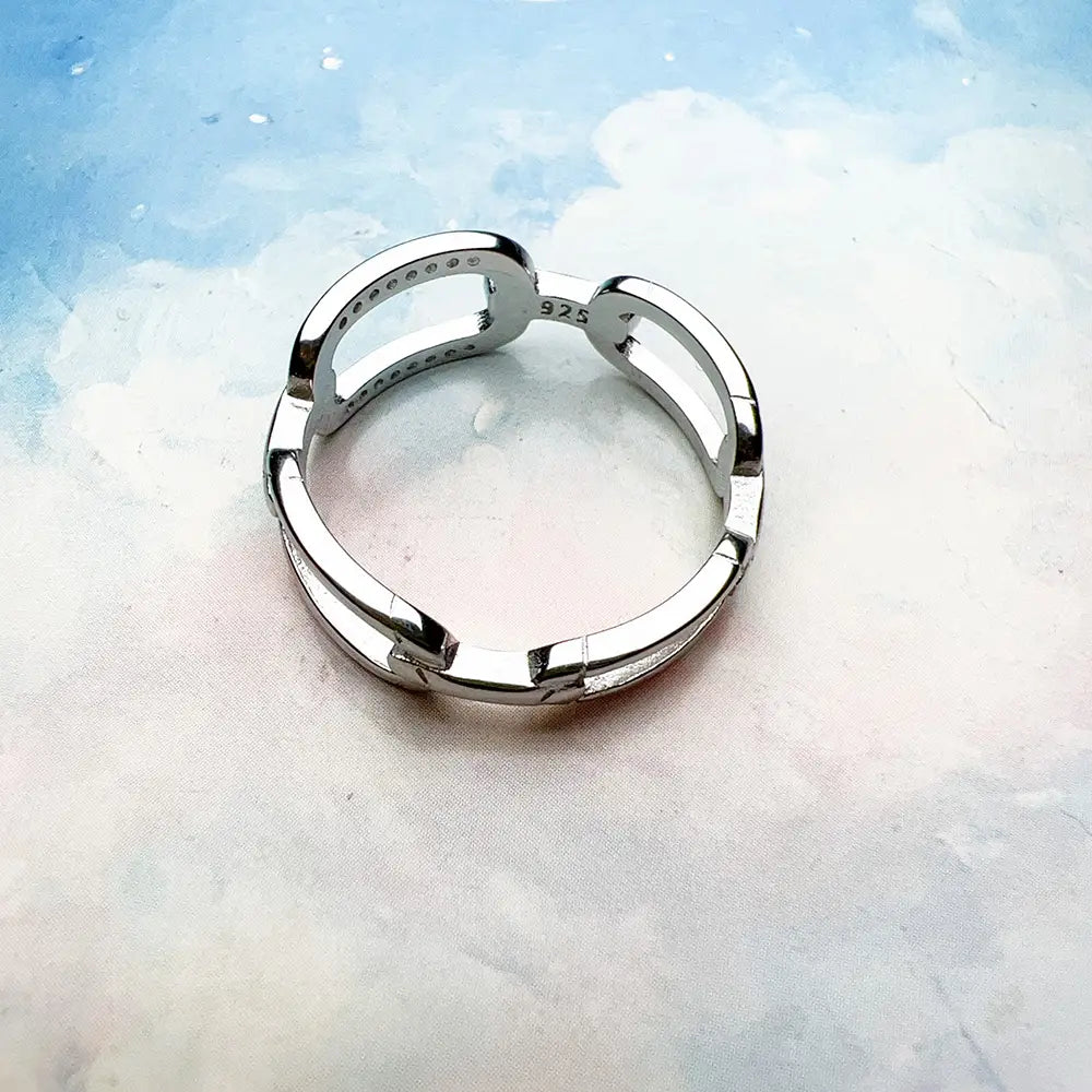 Ring aus Sterlingsilber-Gliedern mit Zirkonia in schlankem Sterlingsilber 925, mit modernem geometrischem Design, ineinandergreifenden Bändern und dezent eingravierten Details.