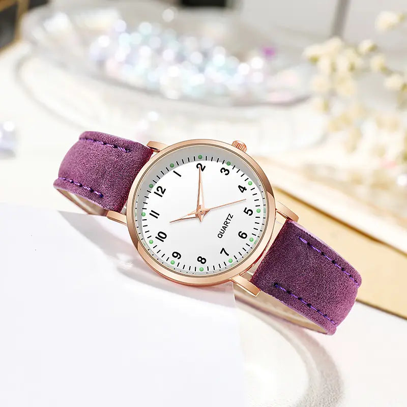 A rose gold women leather quartz watch with a delicate purple suede strap, rose gold-tone case, and white dial featuring minimalist black numerals and green accent markers.