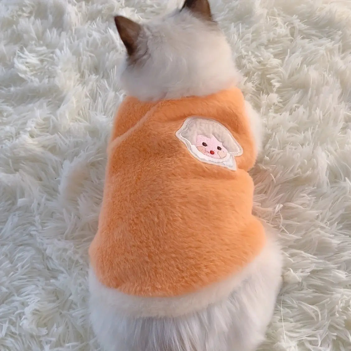 Suéter de gato esponjoso color naranja, elaborado con material mullido, con un aplique bordado de carita de cerdito color blanco, diseñado como ropa de gatitos y accesorios para gatos para uso en invierno