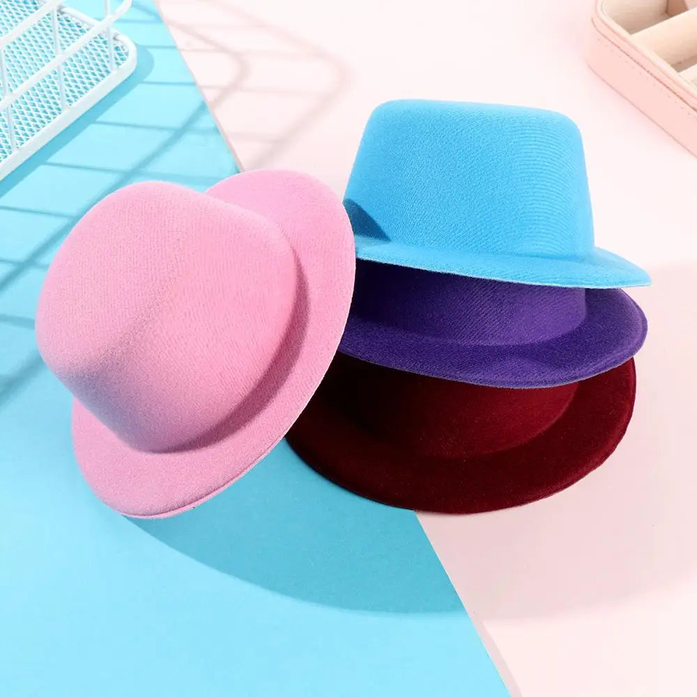 Un ensemble de trois accessoires de mode pour chapeau de poupée en peluche aux couleurs pastel, en rose tendre, bleu ciel et violet profond, pour des poupées de 60 cm.