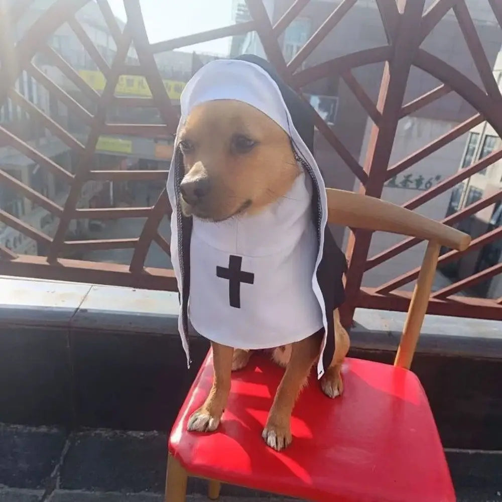 Un perro mascota color canela que lleva un disfraz de monja blanco y negro de fibra de poliéster con un emblema de cruz, diseñado para uso en perros o gatos.