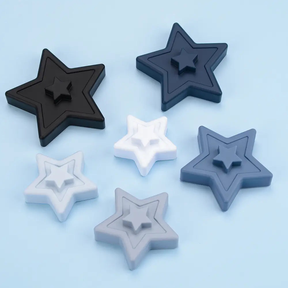 Set of five star-shaped silicone stacking blocks in black white and gray with a layered design for pastel Montessori toys.