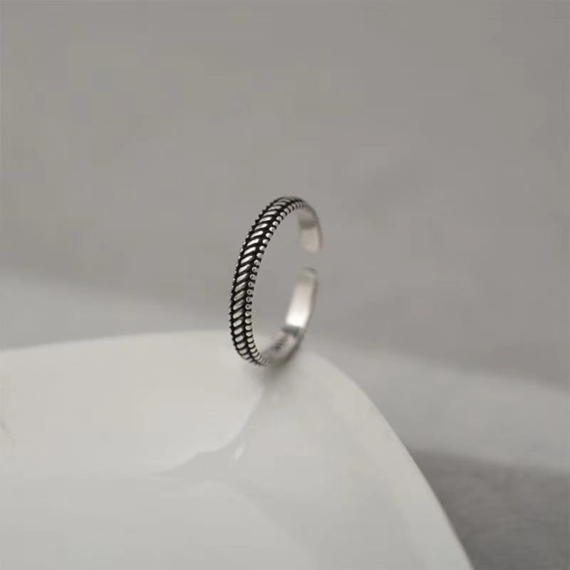 Un anillo para el dedo del pie trenzado de plata de ley pulida y elegante, con un diseño texturizado.
