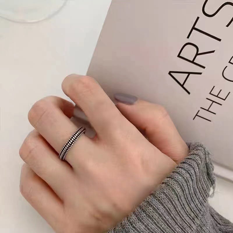 Un anillo para el dedo del pie trenzado de plata de ley delicado, con un diseño texturizado que se lleva en un dedo.