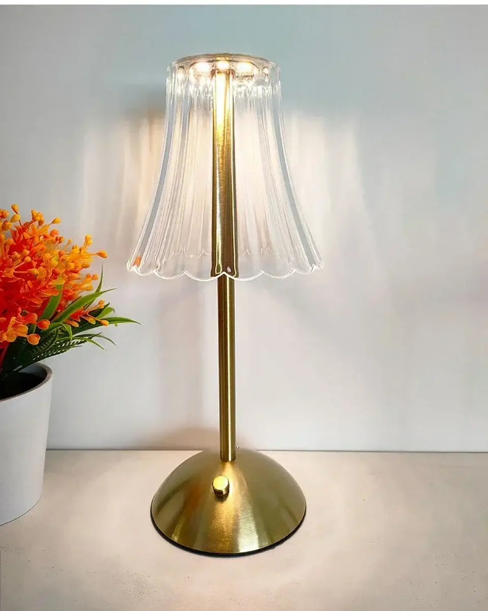 Ein zarter transluzenter Glasschirm mit gefluted Kanten auf einer schlanken, messingfarbenen wiederaufladbaren Tischlampe als stilvolle Lichtquelle.