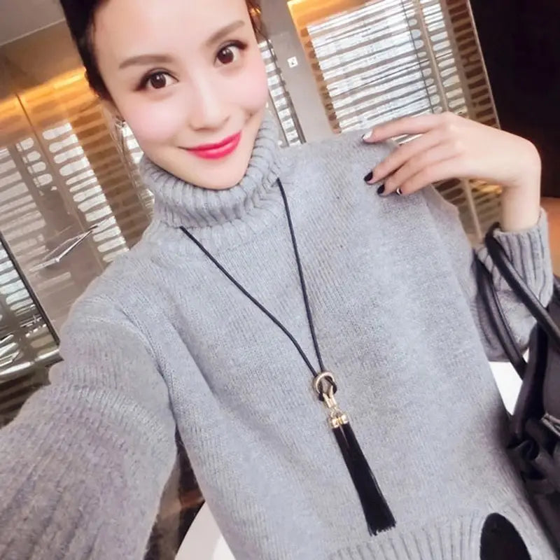Pull col roulé gris associé à un long collier à gland noir en alliage de zinc, comportant un type de chaîne adapté aux femmes.