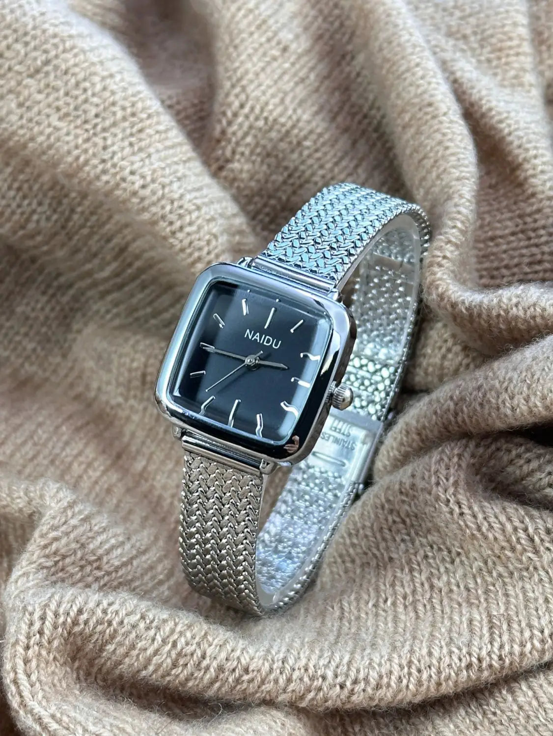 Minimalist square quartz watch for women featuring a silver mesh bracelet with a square black dial and minimalist white hour markers.