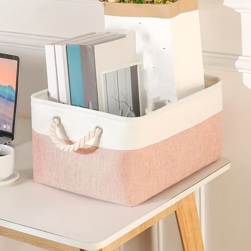 panier de rangement en tissu pliable rose pastel et blanc avec des poignées en corde tressée pour une organisation polyvalente.