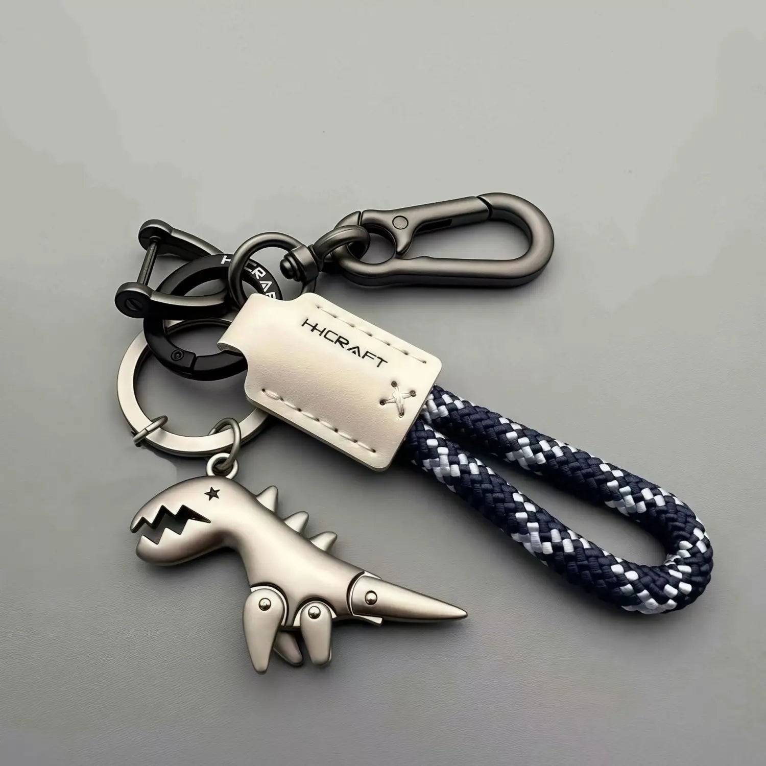 Silver dinosaur leather keychain bag pendant with a black and white braided rope strap.