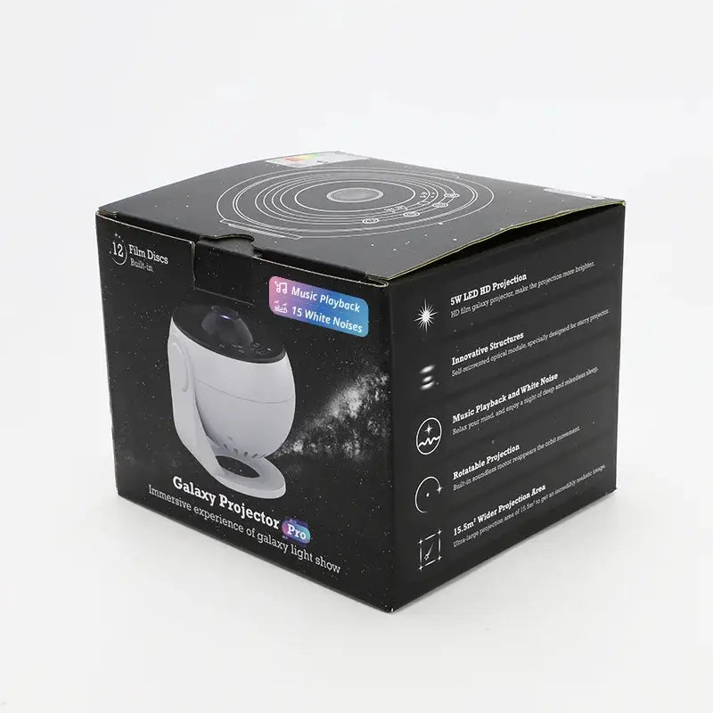 Schwarze Box-Verpackung eines Galaxy-Projektors „Pro“, mit einem weißen und schwarzen Projektor sowie Text, der 12 Filmdiscs hervorhebt, Wiedergabefunktionen für Musik und HD-LED-Projektionseigenschaften für weißes Rauschen und Planetenscheiben.