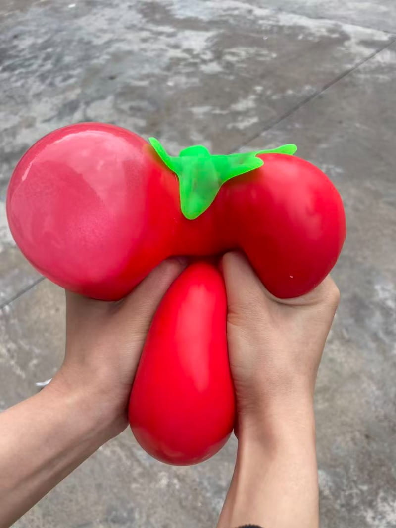 Jumbo strawberry slow rising sensory fidget toy in the shape of a red tomato stress ball with a green stem.