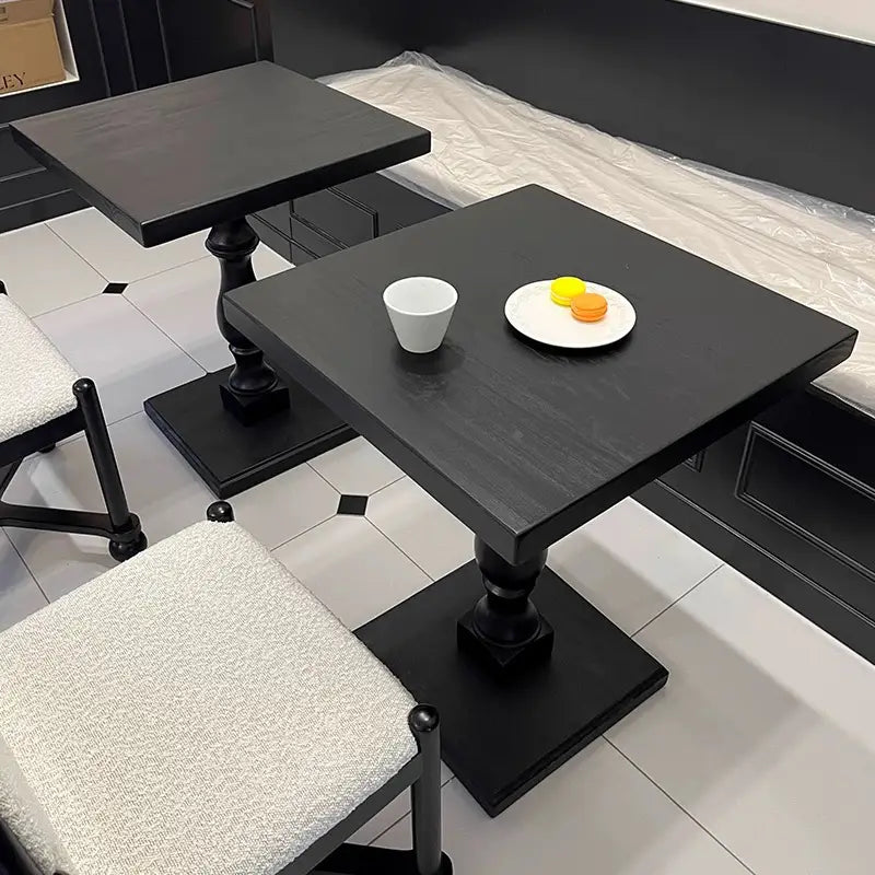 black wooden pedestal round accent tables with square tops, ornate turned legs, and a matte finish