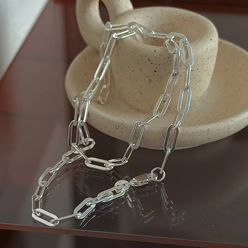 Un collar minimalista de cadena tipo eslabones de papel de plata de ley 925 en tono plateado, con un diseño de eslabones refinado.