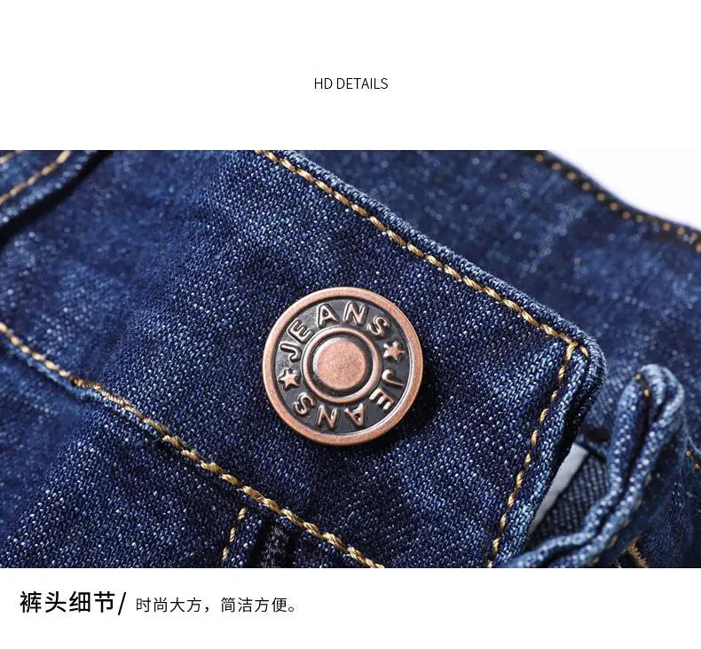 a bronze-colored circular button engraved with jeans on dark blue stretch cotton denim fabric of men’s stretch cotton straight jeans casual trousers