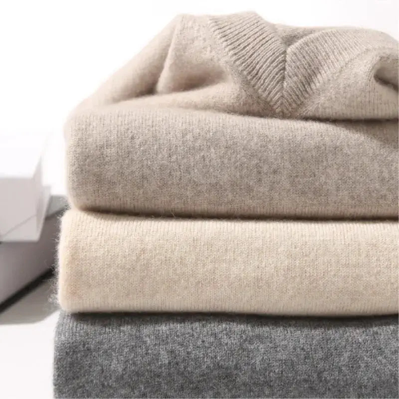 Stack of soft neutral-toned men cashmere v neck pullover sweaters in beige and gray hues.