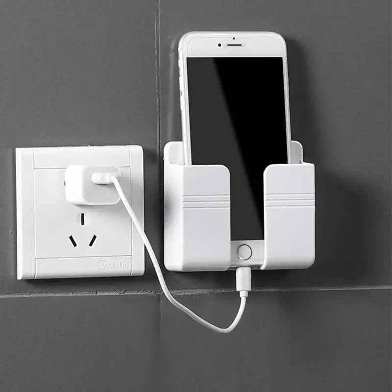 White plastic wall mount phone charging holder securely holding a smartphone with charging cable plugged into an outlet.
