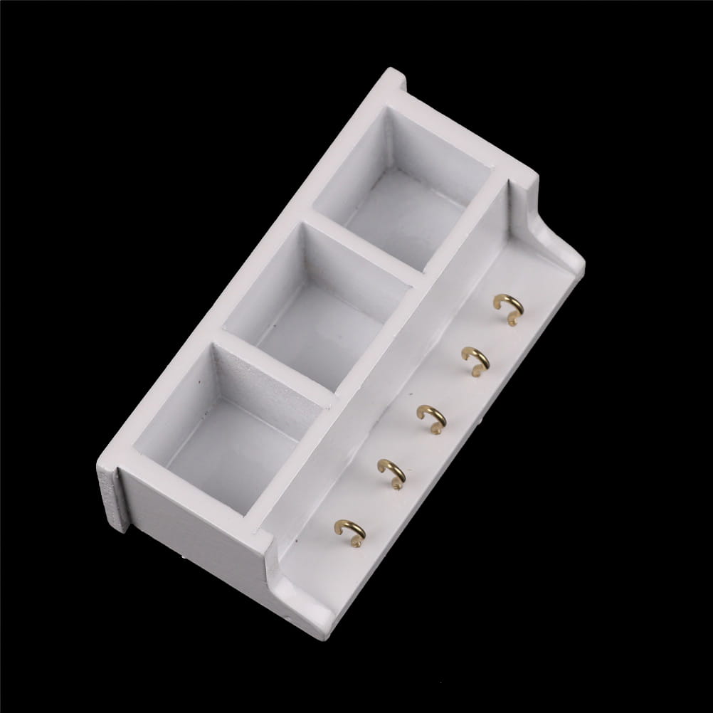 Weißes Kunststoff-Miniatur-Wandregal für eine Puppenstube mit drei rechteckigen Abteilen und fünf goldfarbenen Haken entlang der Seitenkante.