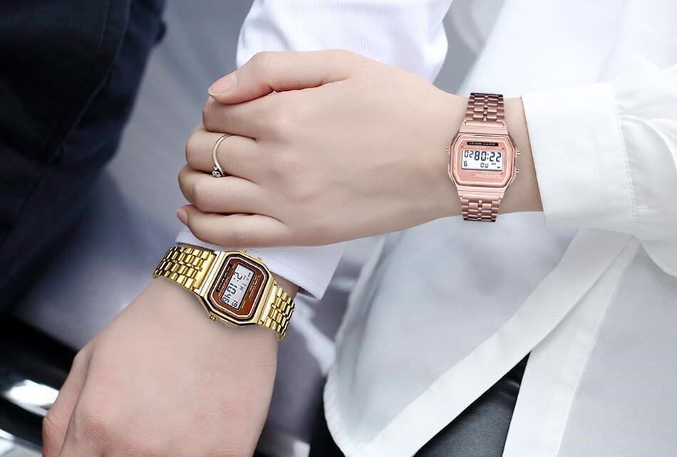 Des hommes ont conduit une montre numérique en or rose, dotée d’une bande métallique en acier inoxydable et d’un écran rectangulaire.