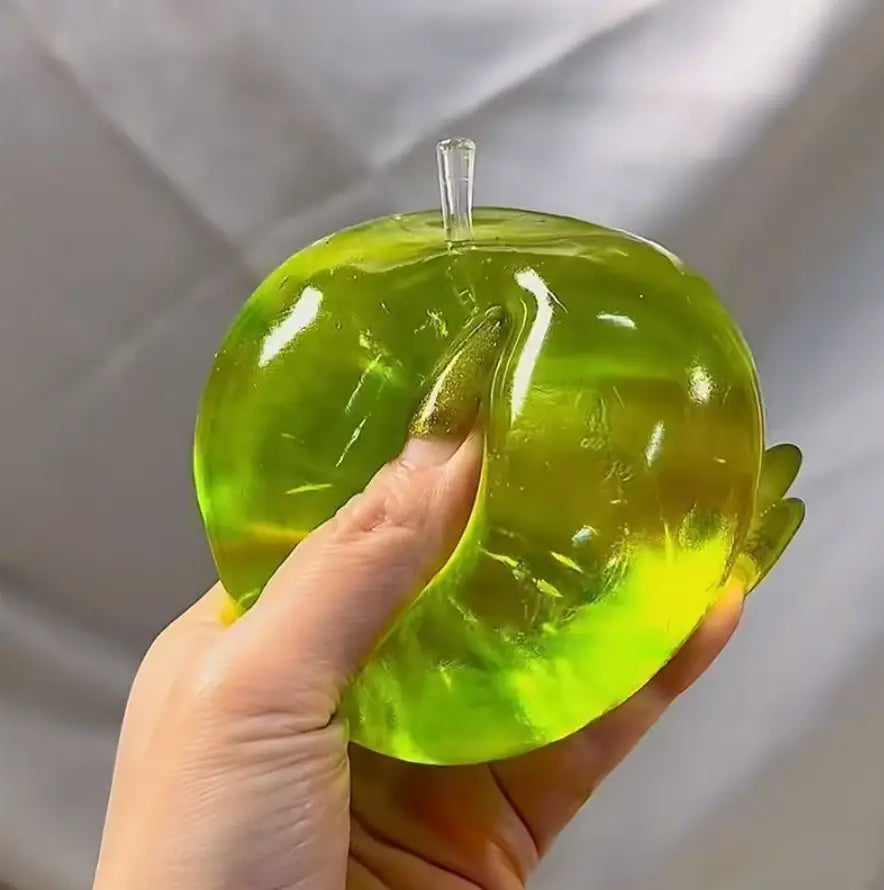 une balle anti-stress souple verte en forme de pomme vert citron translucide, avec une tige en plastique transparente, vue de face.