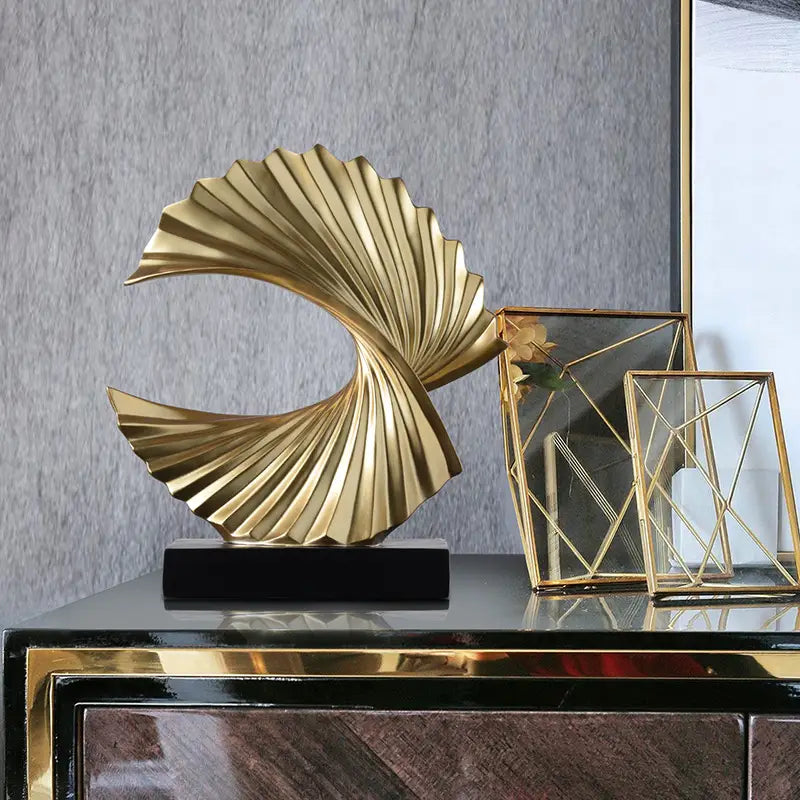 Art deco gold wave sculpture tabletop decor featuring a golden metallic fan-like spiraling design on a black base.