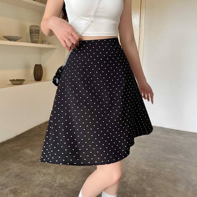 Falda línea A negra con lunares blancos y pretina ajustada, adecuada como alternativa a una falda midi línea A roja con lunares