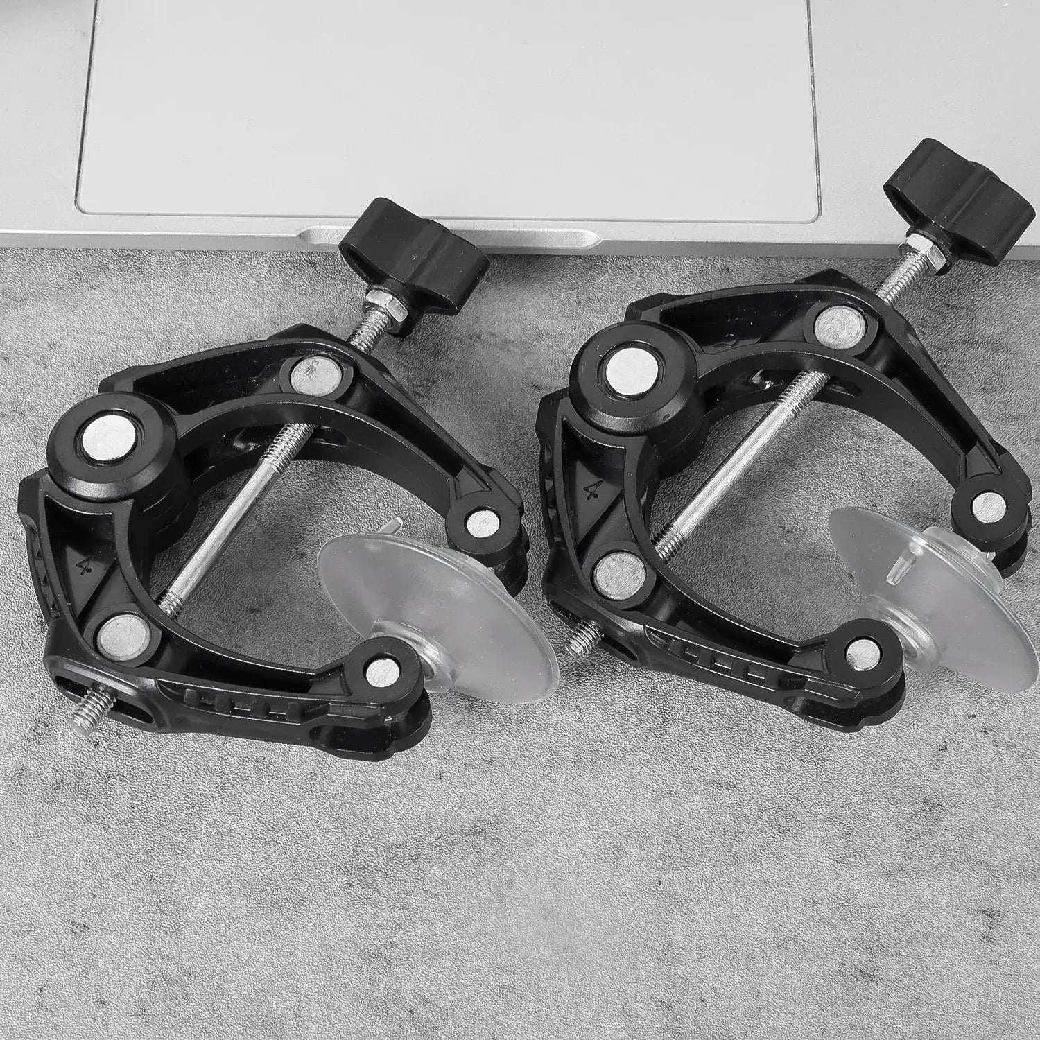black plastic suction cup mount clamps with adjustable threaded rods and black knob handles used in a phone screen separator tool with minimalist style design