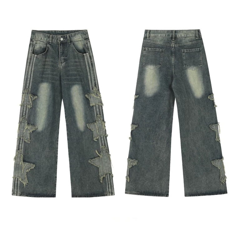 Jeans en denim délavé et déchiré baggy style y2k gris foncé, comportant des patchs en forme d’étoiles déchirées le long des coutures externes de la jambe.