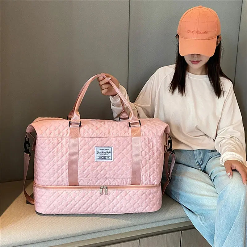 Bolsa de viaje tipo duffel acolchada rosa con asas a juego y correa para el hombro, diseñada como un tote weekender grande.